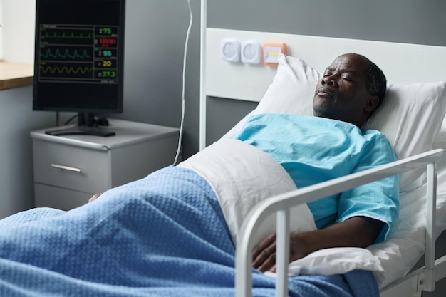 Afroamerykanin pacjent leżący na łóżku na oddziale szpitalnym z monitorem kontrolującym stan serca