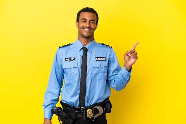 Afroamerykanin Policjant Nad Odosobnioną żółtą Powierzchnią Pokazujący I Unoszący Palec Na Znak Najlepszych