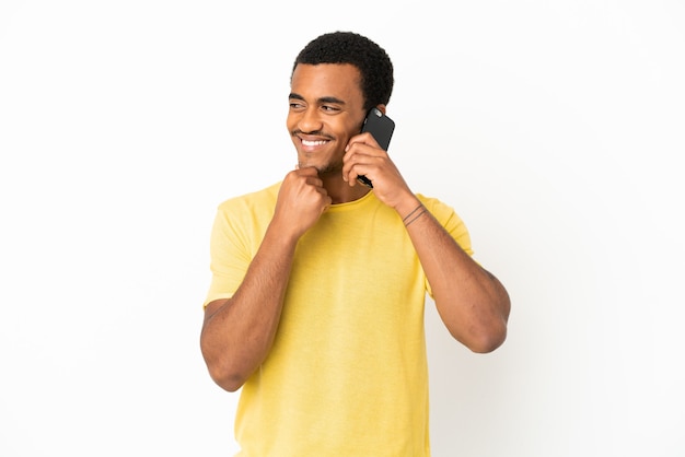 Afroamerykanin, przystojny mężczyzna, używający telefonu komórkowego na białym tle, patrząc w bok i uśmiechnięty