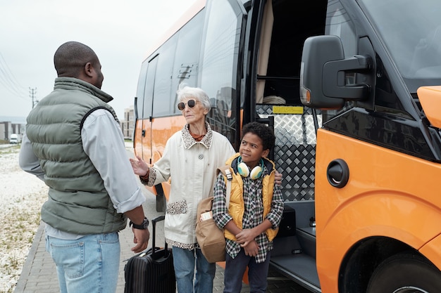 Afroamerykanin W Kamizelce, Wsadzający Babcię I Syna Do Autobusu I Słuchający Obietnicy Babć