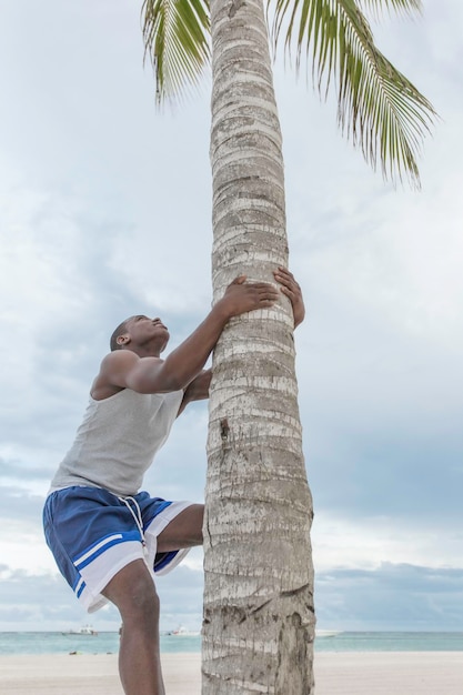 Afroamerykanin wspinający się po palmie