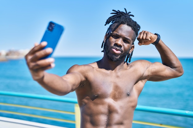 Afroamerykanka bez koszuli robi selfie smartfonem nad morzem