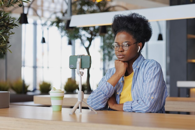 Afroamerykanka blogerka w coworkingu komunikuje się przez wideoczat lub ogląda szkolenie