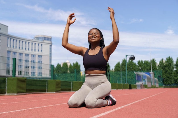 Afroamerykanka czuje się szczęśliwa po biegu na długim dystansie na torze na boisku sportowym