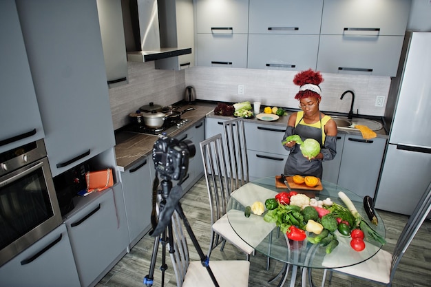 Zdjęcie afroamerykanka filmuje swoją audycję na blogu o zdrowej żywności w domowej kuchni trzyma kapustę