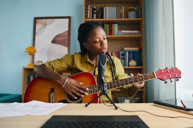 Afroamerykanka grająca na gitarze akustycznej w domu.