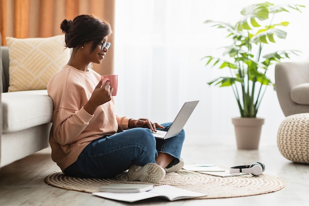 Afroamerykanka, korzystająca z laptopa, pijąca kawę w domu