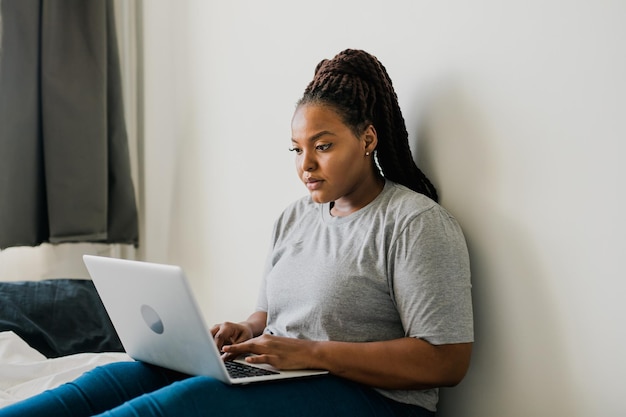 Afroamerykanka, młoda kobieta, korzystająca z laptopa na technologiach łóżka oraz komunikacji i sieci społecznościowej