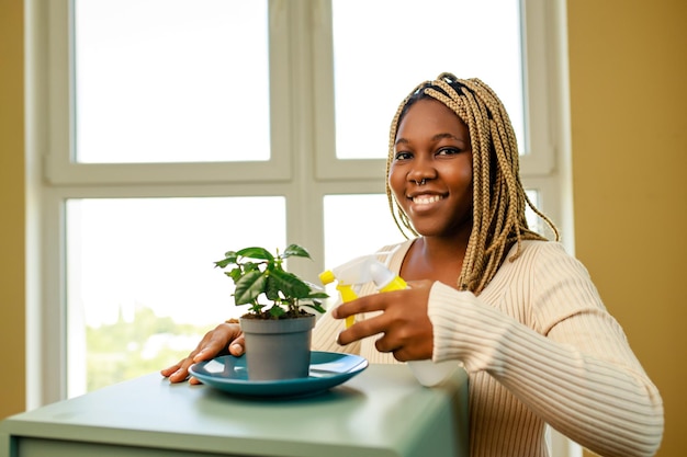 Afroamerykanka opiekująca się i uprawiająca roślinę w domu