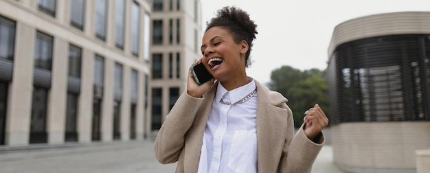 Afroamerykanka, przedsiębiorczyni z zadowoloną twarzą i uśmiechem, mówi później przez telefon komórkowy