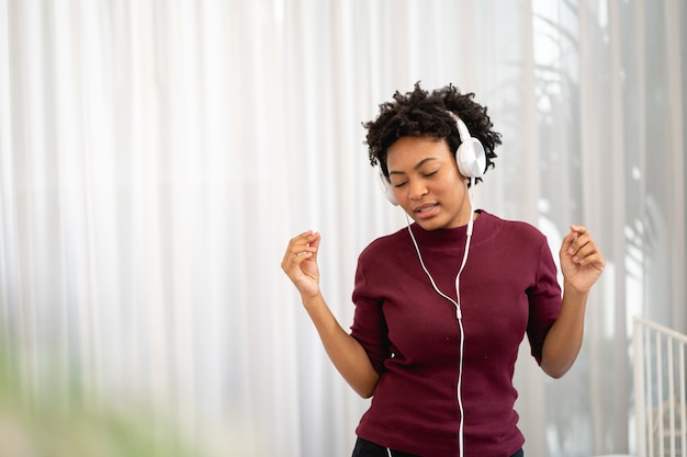 Afroamerykanka słucha muzyki przez słuchawki w salonie