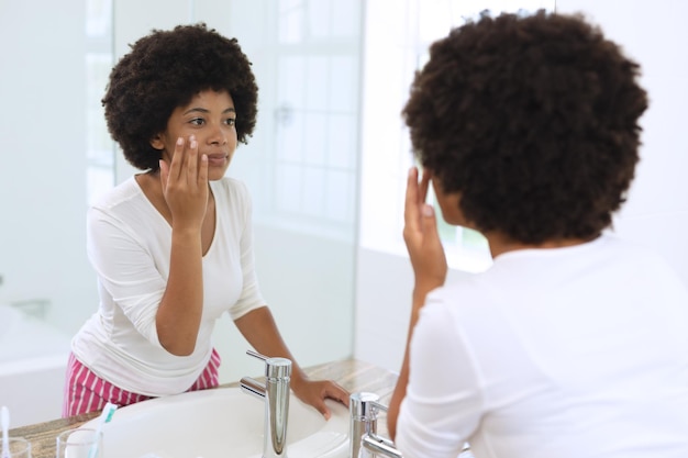 Afroamerykanka stojąca w łazience i nakładająca krem do twarzy
