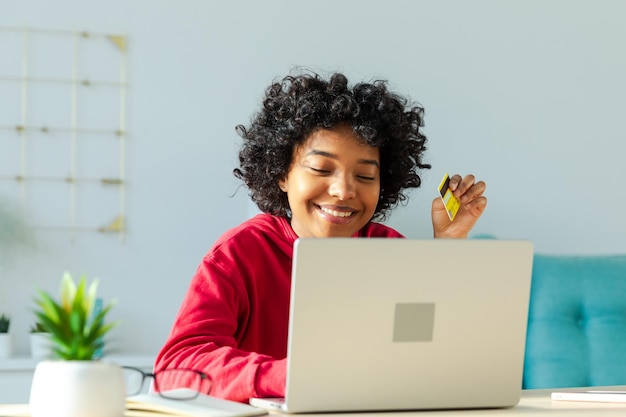 Afroamerykanka używająca laptopa do zakupów online płacąc złotą kartą kredytową dziewczyna siedząca w