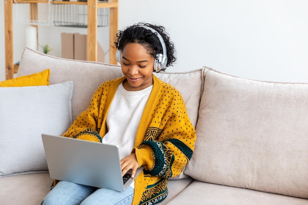 Afroamerykanka używająca laptopa w domowym biurze, patrząca na ekran, pisząca na czacie, czytająca, pisząca