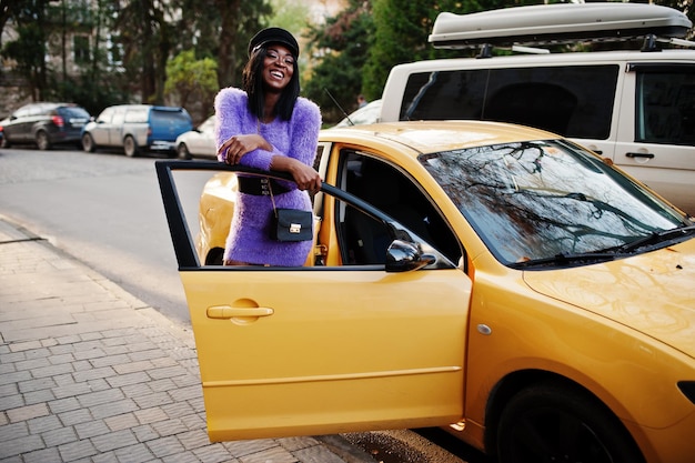 Afroamerykanka W Fioletowej Sukience I Czapce Pozowała Do żółtego Samochodu