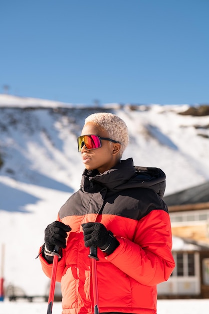 Afroamerykanka z kijkami narciarskimi stojąca na zaśnieżonej górze zimą