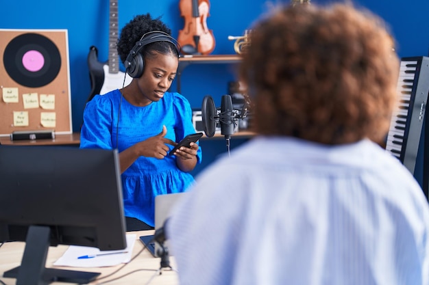 Afroamerykanki muzycy używający smartfona w studiu muzycznym