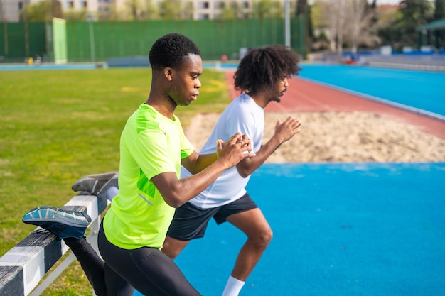 Afroamerykańscy biegacze rozgrzewają się, rozciągając nogi na świeżym powietrzu.