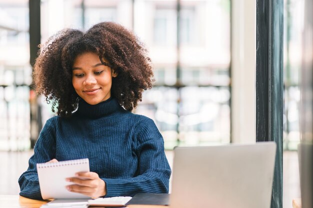 Afroamerykańska bizneswoman lub księgowy z włosami afro używając kalkulatora wykresów i wykresy do analizy danych rynkowych bilansów rachunków i zysków netto