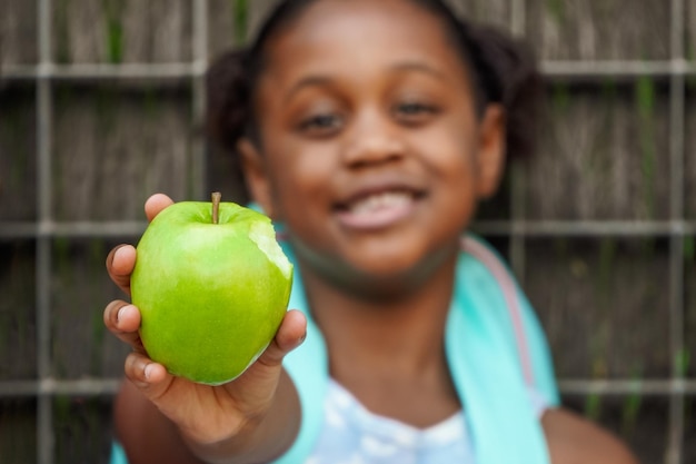 Afroamerykańska uczennica z plecakiem je zielone jabłko