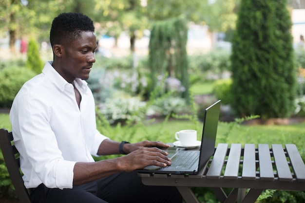Afroamerykański biznesmen pracujący przy laptopie w kawiarni