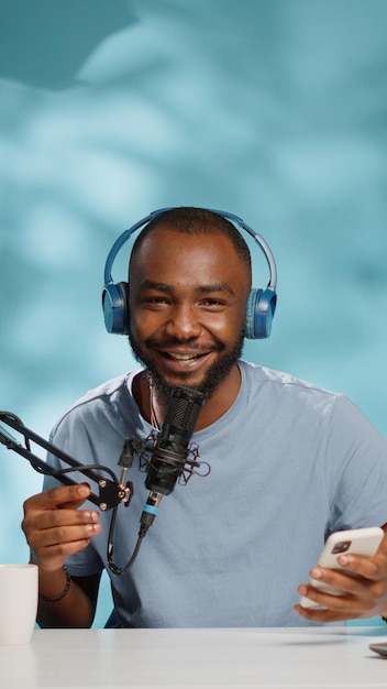 Afroamerykański bloger nagrywający wideo w aparacie na kanał w studio. Czarny vloger wykorzystujący nowoczesny sprzęt i smartfon do nagrywania podcastów w mediach społecznościowych. vlogowanie influencerów