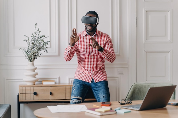 Afroamerykański deweloper oprogramowania w zestawie słuchawkowym VR testujący gry 3D i aplikacje w nowoczesnym biurze domowym Przyjmując technologię i rozwój oprogramowania