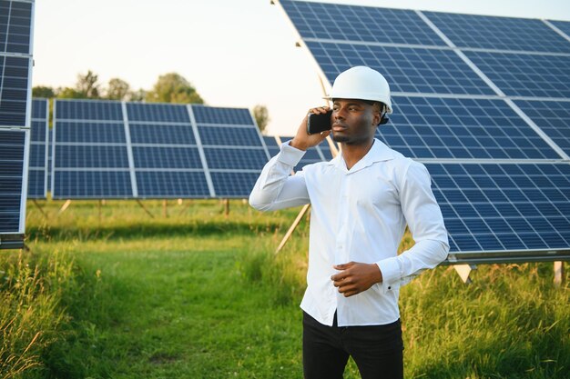 Afroamerykański inżynier w białej koszuli i kapeluszu pracuje nad polem paneli słonecznych Koncepcja energii odnawialnej słonecznej