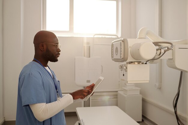 Afroamerykański klinicysta płci męskiej wybierający ustawienia urządzenia rentgenowskiego w tablecie
