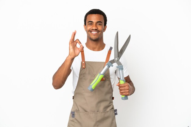 Afroamerykański ogrodnik mężczyzna trzyma nożyce do przycinania na białym tle pokazując znak ok palcami