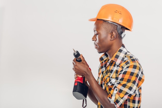 Afroamerykański pracownik budowlany w kasku używa elektrycznego śrubokręta
