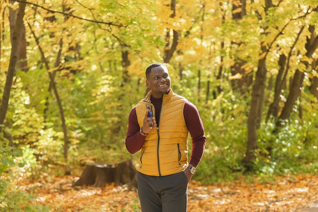 Afroamerykański student spacerujący po parku w sezonie jesiennym