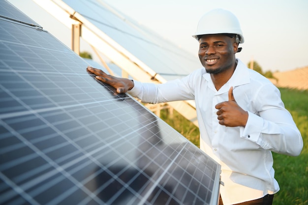 Afroamerykański technik sprawdza konserwację paneli słonecznych Czarny inżynier w stacji słonecznej