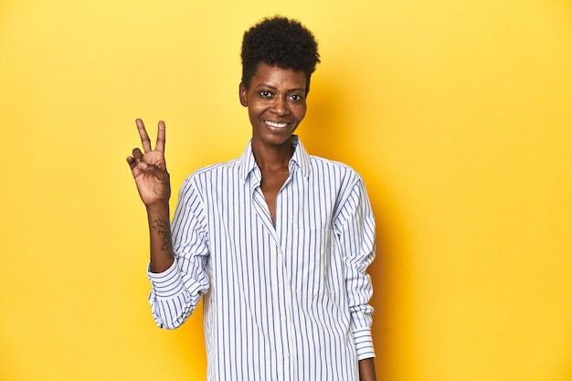 Afrykańska bizneswoman niebieska prążkowana koszula żółty tło radosny i beztroski