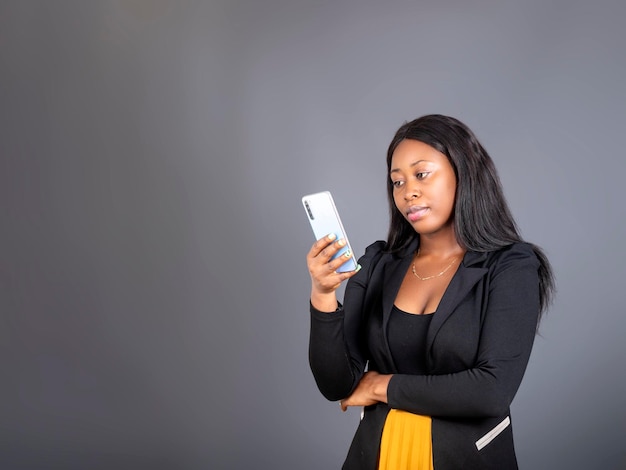 Afrykańska dziewczyna trzyma patrząc na telefon komórkowy, wysyłając SMS-y na telefon komórkowy