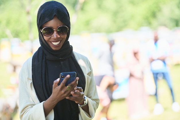 afrykańska kobieta biznesu korzystająca ze smartfona ubrana w tradycyjne islamskie ubrania