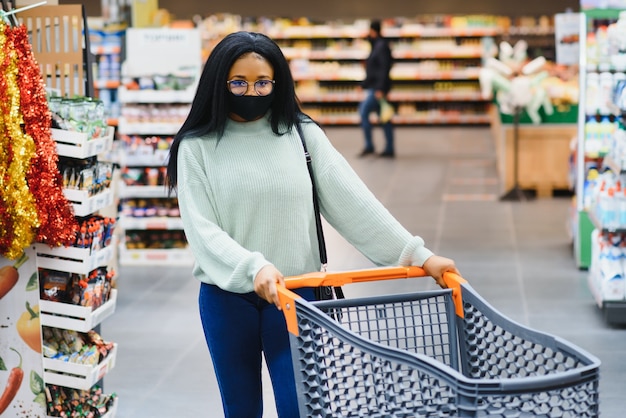 Afrykańska Kobieta Nosi Jednorazową Maskę Medyczną. Zakupy W Supermarkecie Podczas Wybuchu Pandemii Koronawirusa. Czas Epidemii.