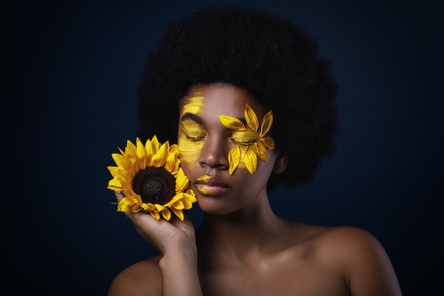 Afrykańska kobieta z słonecznikowym i kreatywnie makijażem na jej twarzy