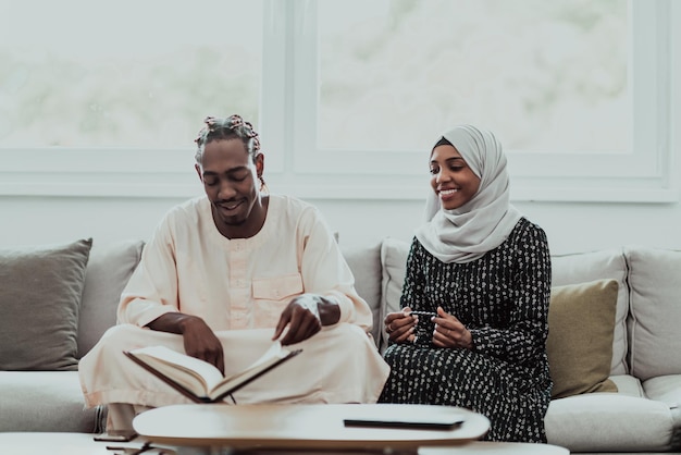 Afrykańska para muzułmańska w domu w Ramadanie czyta książkę o islamie ostrokrzewu Koran. Zdjęcie wysokiej jakości