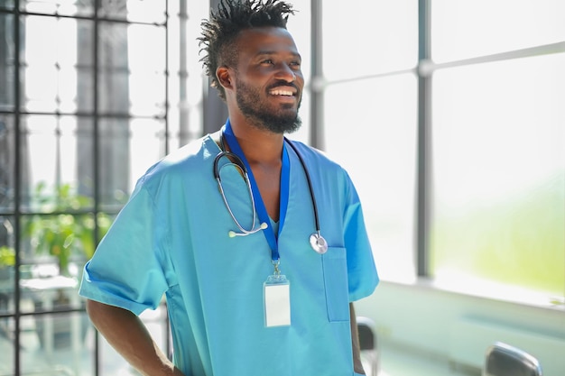 Afrykański lekarz mężczyzna ubrany w fartuch medyczny stojący w szpitalnym korytarzu