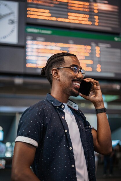 Afrykański mężczyzna dzwoni do przyjaciela, gdy czeka na stacji kolejowej