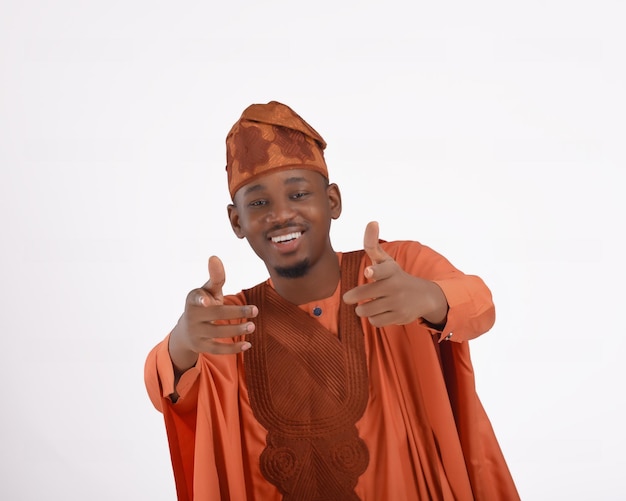 Afrykański mężczyzna ubrany w tradycyjny strój joruba z Nigerii, agbada, podekscytowany, wskazując na kamerę