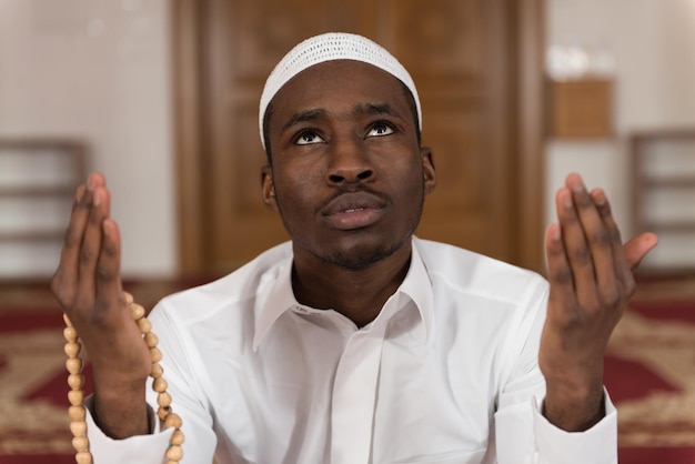 Afrykański muzułmanin odmawiający tradycyjną modlitwę do Boga, nosząc tradycyjną czapkę Dishdasha