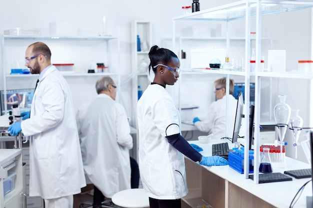 Afrykański naukowiec i jej koledzy przeprowadzają eksperymenty w sterylnym laboratorium. Wieloetniczny zespół naukowców pracujących w laboratorium mikrobiologicznym testującym rozwiązanie do celów medycznych.