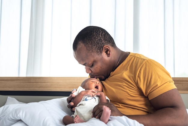 Afrykański ojciec dmuchnie powietrzem na czoło swojego 12-dniowego nowonarodzonego syna o czarnej skórze, aby przekonać go do snu