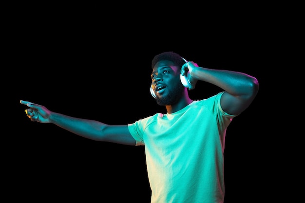 Afrykański portret młodego mężczyzny na ciemnym tle studyjnym w neonowej koncepcji ludzkich emocji mimika sprzedaży młodzieży ad