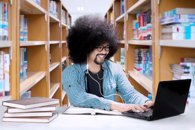 Afrykański student używający słuchawek w bibliotece