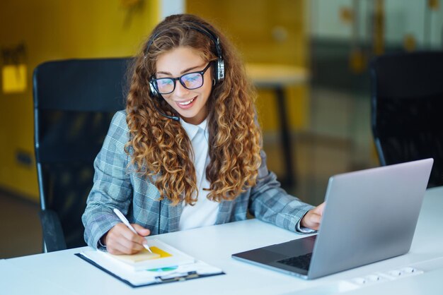 Agent call center z zestawem słuchawkowym pracujący na infolinii wsparcia w nowoczesnym biurze Wideokonferencja