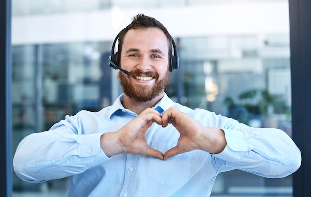 Zdjęcie agent callcenter z uśmiechem i dłońmi serca w portrecie uwielbia pracę obsługi klienta i informacje zwrotne emoji gestów dłoni i konsultant płci męskiej jest zadowolony z pracy w contact center i wsparciu technicznym