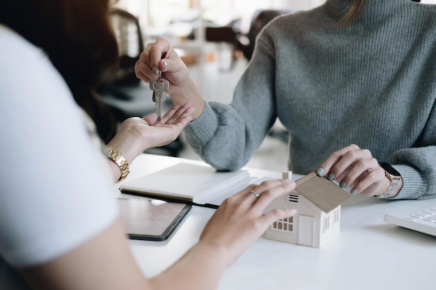 Zdjęcie agent nieruchomości daje kobiecie klucze do domu i podpisuje umowę w biurze